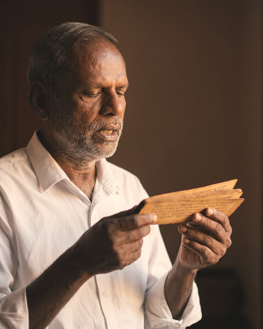 A Nadi reader holding a palm leaf as he reads from it