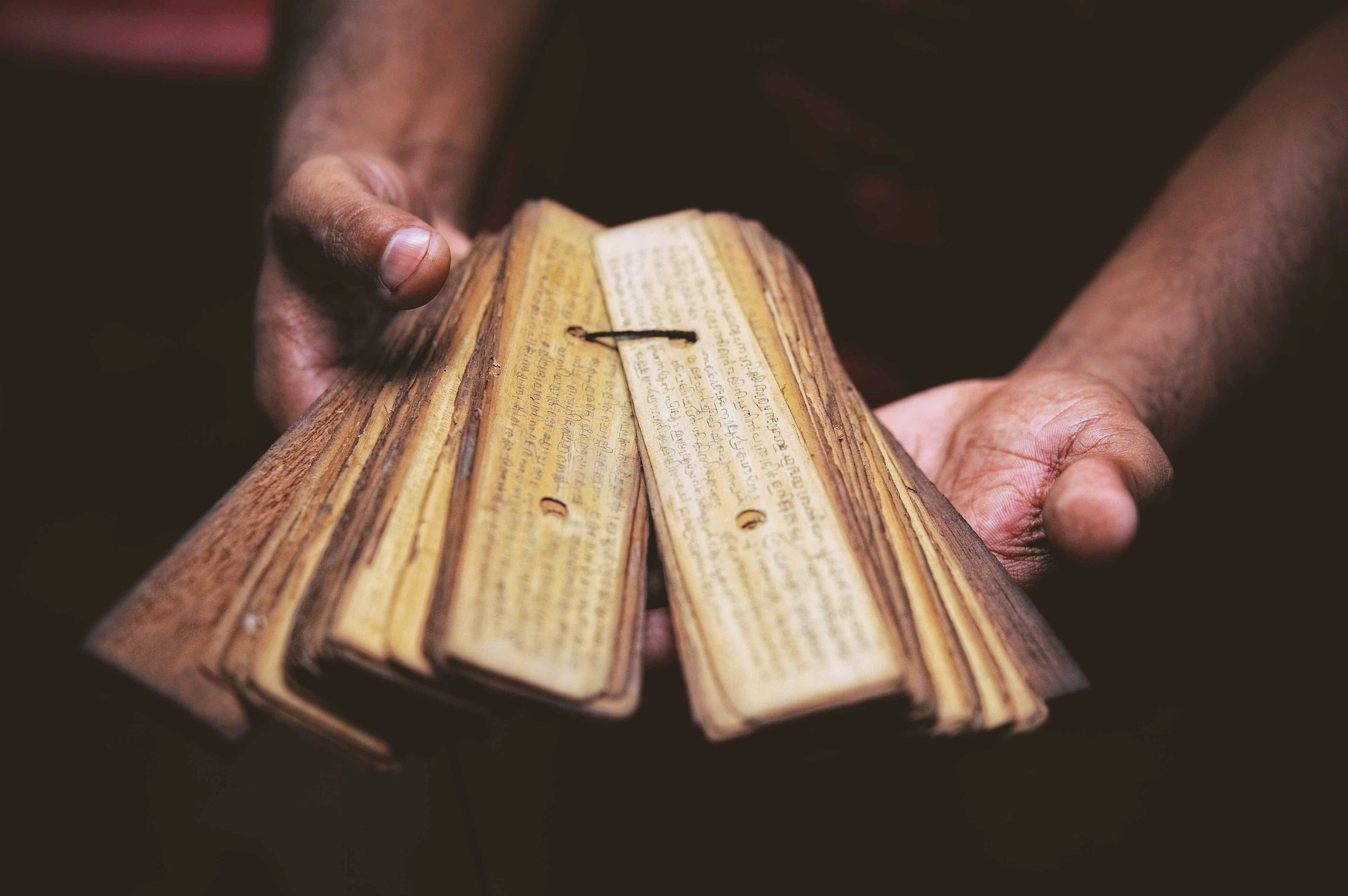 Inscribed palm leaves fanned open between two hands