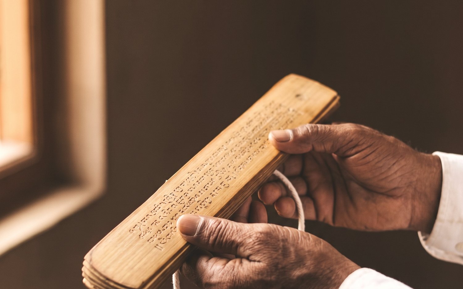 A reader’s hands holding an inscribed palm leaf
