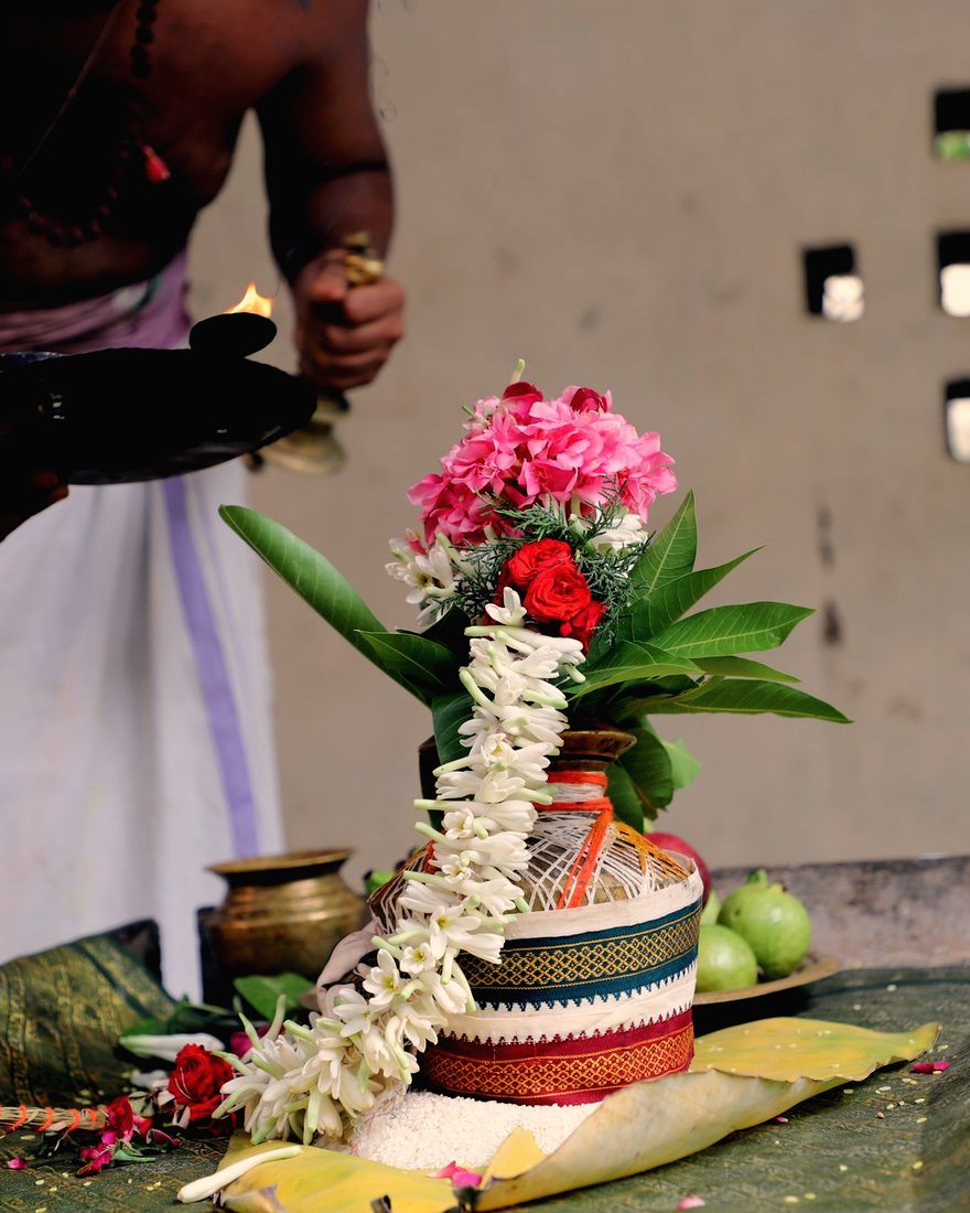 A garlanded kalasha vessel dressed with mango leaves and flowers