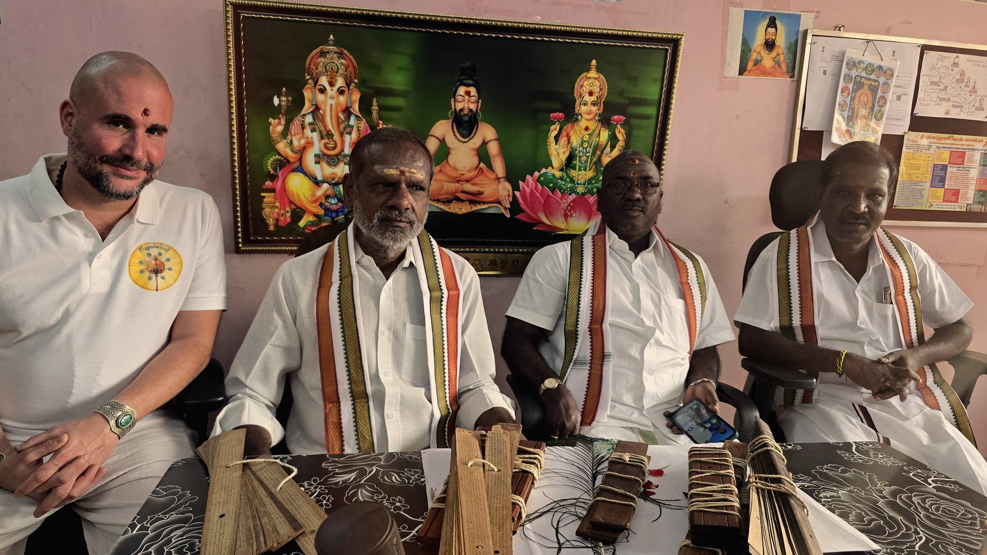 Our founder seated with three of the readers behind a table of open palm-leaf bundles