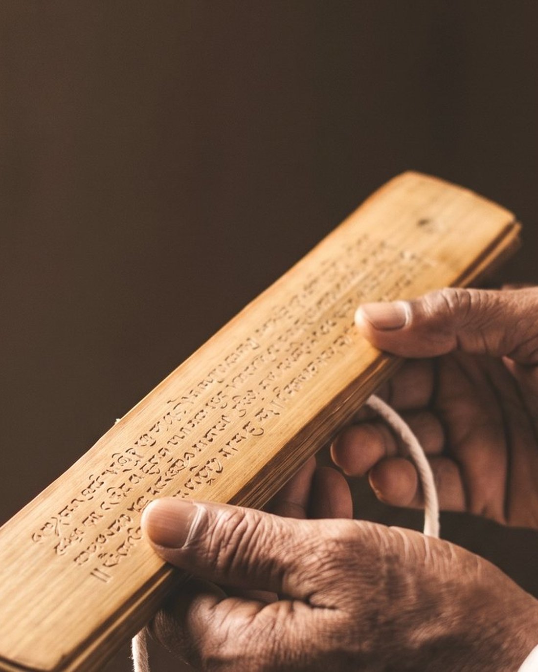 An inscribed palm leaf held open in a reader's hands