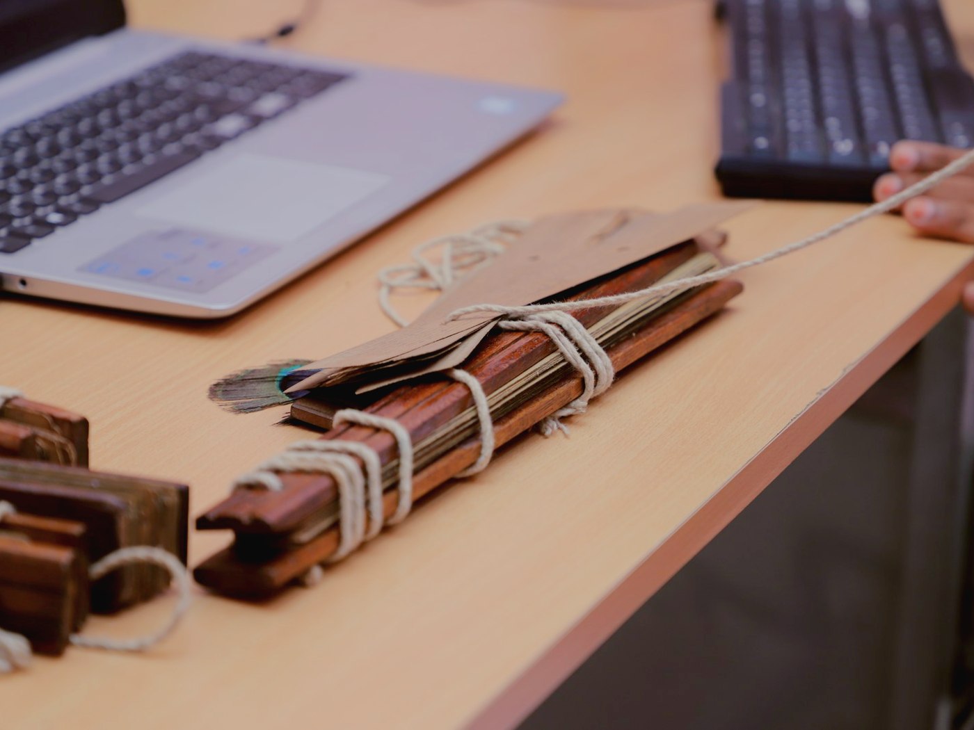 A palm-leaf bundle on the desk beside the laptop the session runs on
